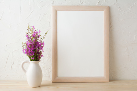Frame mockup with purple wild flowers bouquet. Portrait white frame mockup. Empty white frame mockup for presentation artwork design.の写真素材