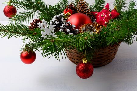 Christmas red ornaments and snowy decorated pine cone table centerpiece. Christmas background with arrangement in wicker basket.の写真素材