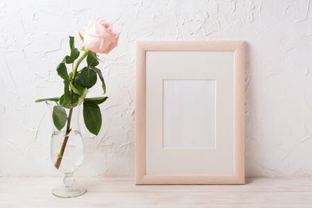 Wooden frame mockup with rose in exquisite glass vase. Empty frame mock up for presentation artwork.の写真素材
