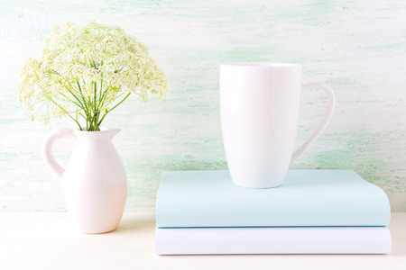White cappuccino mug mockup with wild meadow flowers in pitcher.  Empty mug mock up for design presentation.  の写真素材