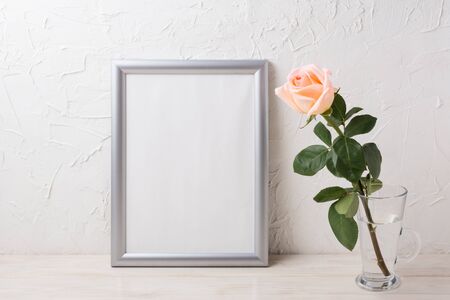 Silver frame mockup with creamy pink rose in glass vase. Empty frame mock up for presentation artwork.の写真素材