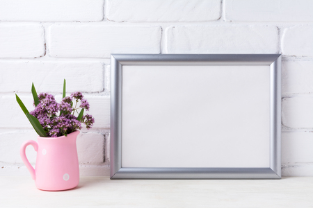 Silver landscape frame mockup with purple field flowers in polka dot pink rustic pitcher vase. Empty frame mock up for presentation artwork. Template framing for modern art.の写真素材