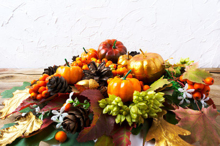 Fall greeting with pumpkins, leaves and seeds table centerpiece on the rustic wooden table. Thanksgiving  background with berries and cones wreath, copy spaceの写真素材
