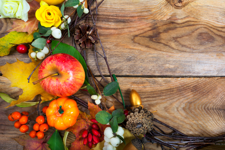 Thanksgiving holidays background with pumpkins, snowberry, apple, maple leaves and yellow roses wreath, copy spaceの写真素材