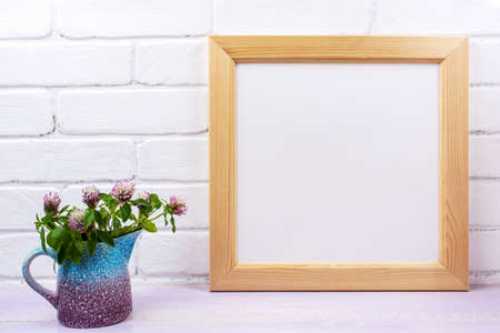Wooden square picture frame mockup with pink clover in the blue pitcher vase. Empty frame mock up...