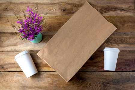 Brown paper shopping bag and two coffee paper cups with lids mockup with purple wildflowers. Kraft recycled grocery shopping bag mock up for branding presentation.の写真素材
