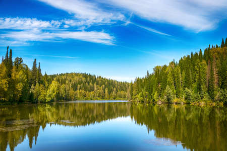Summer landscape with blue cloudy sky reflection in the river water. Tranquil scenic viewの写真素材