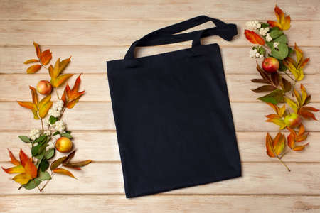 Black canvas tote bag mockup with fall leaves and ghostberry. Rustic linen shopper bag mock up for branding presentationの写真素材