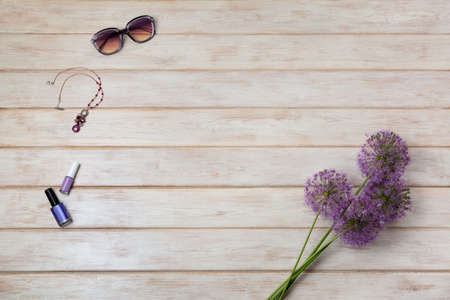 Holiday greeting or social media background with allium purple flowers, sunglasses, necklace and nail polish on the white painted wooden taible, copy spaceの写真素材