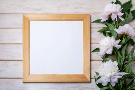 Wooden square picture frame mockup with pale pink peony. Empty frame mockup for presentation design....
