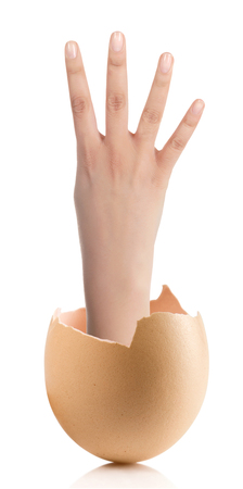 Hand with broken egg isolated on white backround.Image of female hand showing four fingers on a white backgroundの写真素材