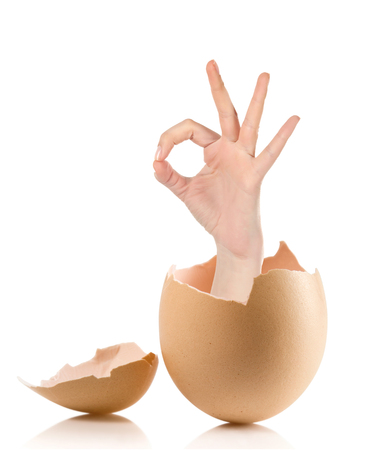 Hand with broken egg isolated on white backround.Female hand showing thumb up ok all right victory hand sign gesture. Gestures and signs. Body language on white backgroundの写真素材