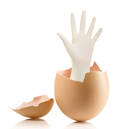 Hand with broken egg isolated on white backround.Hand with Surgical Gloves on white background medical conceptの写真素材