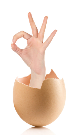 Hand with broken egg isolated on white backround.Female hand showing thumb up ok all right victory hand sign gesture. Gestures and signs. Body language on white backgroundの写真素材