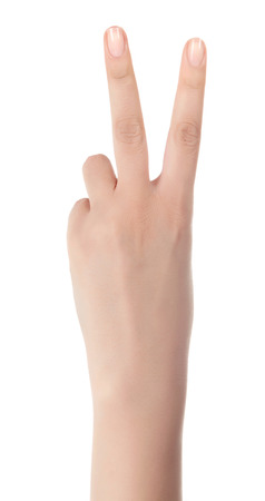 Hand showing the sign of victory and peace. Close up of female hand showing victory sign isolated on white background. Woman hand gesturing peace sign.の写真素材