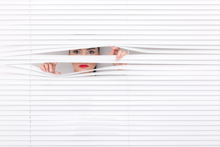 Portrait of a woman looking through out the blindsの写真素材