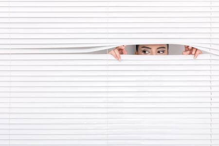 Portrait of a woman looking through out the blindsの写真素材