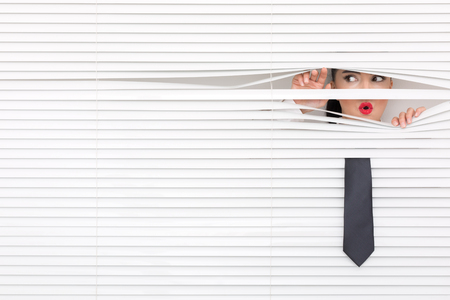 Portrait of a woman looking through out the blindsの写真素材