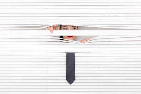 Portrait of a woman looking through out the blindsの写真素材
