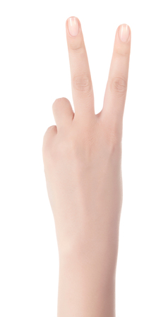 Hand showing the sign of victory and peace. Close up of female hand showing victory sign isolated on white background. Woman hand gesturing peace sign.の写真素材