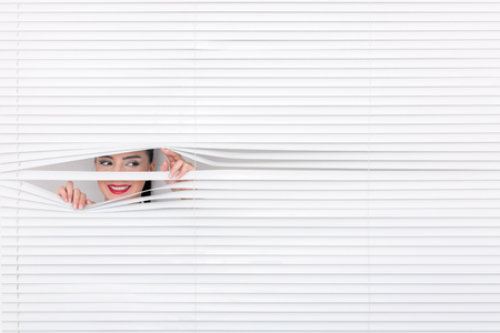 Portrait of a woman looking through out the blindsの写真素材