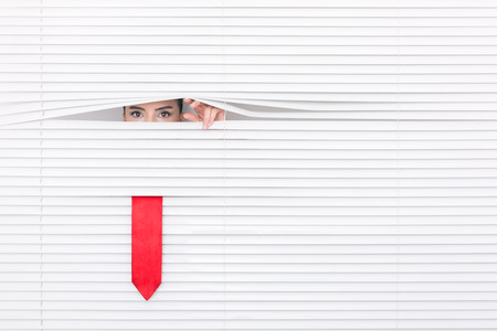 Portrait of a woman looking through out the blindsの写真素材