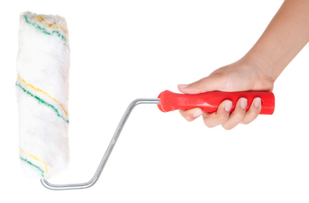 Close-up view of a man's hand with a paint roller, isolated on white background. Wall painting. Interior decorating. Building and trimmingの写真素材