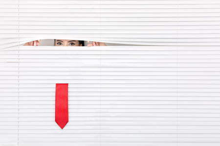 Portrait of a woman looking through out the blindsの写真素材