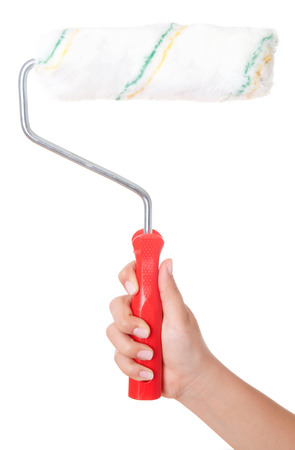 Close-up view of a man's hand with a paint roller, isolated on white background. Wall painting. Interior decorating. Building and trimmingの写真素材