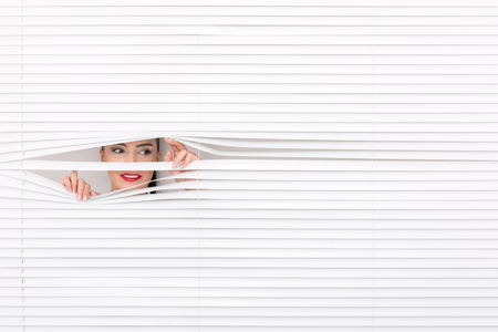 Portrait of a woman looking through out the blindsの写真素材