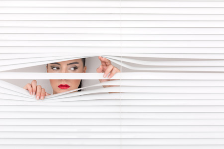 Portrait of a woman looking through out the blindsの写真素材