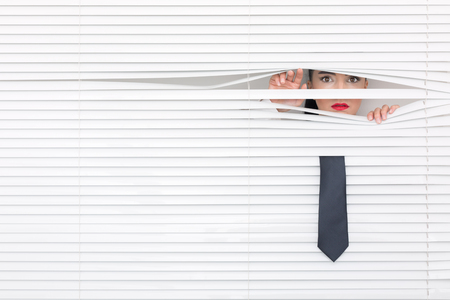 Portrait of a woman looking through out the blindsの写真素材