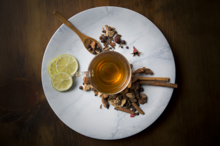 Food background with different black and green dry tea, rose buds cup of hot tea and iron teapot over dark wooden background. Tea drinking concept. Top view. Square imageの写真素材