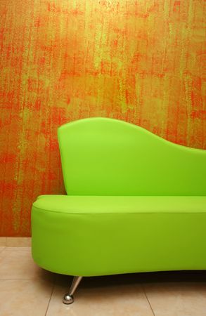 green sofa detail over a stylish red wall-paperの写真素材