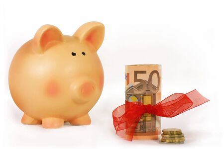 piggy bank and bankroll with a red ribbon isolated in white backgroundの写真素材