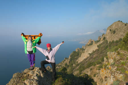 Happy girls standing on the peak above the seaの写真素材