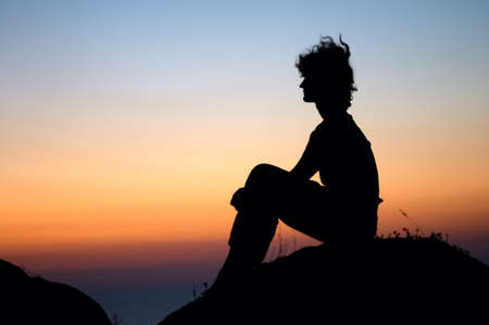girl looking for sunset on the top of stoneの写真素材