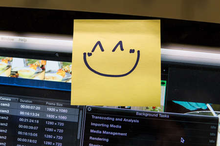 smiley face written on yellow post it note on computer screen