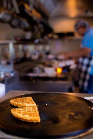fresh piece of waffles on black plate with blurred cooking chef in background, selective focusの写真素材