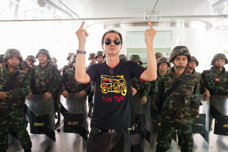 BANGKOK - MAY 25: Unidentified protestor showing middle finger hand sign front of soldiers wall, May...