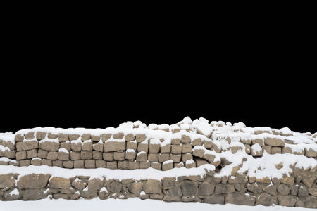 snow covered stone wall isolated on black backgroundの写真素材