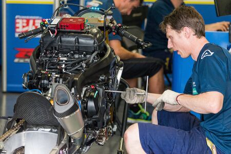 BURIRAM - MARCH 20 : Voltcom Crescent Suzuki race technician inspecting race bike in pit at Chang international circuit on March 20 2015, Buriram, Thailandのeditorial素材