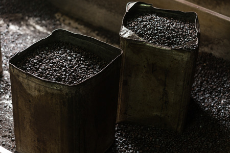 roasted black coffee beans in metal buckets low keyの写真素材