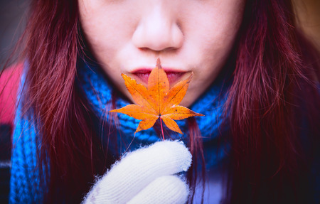 woman holding orange maple leaf and kiss, vintage filtered colorの写真素材