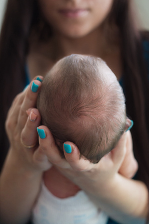 Mom gently holds the baby's head in her handsの写真素材