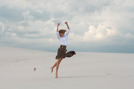The girl is flying happily in the desertの写真素材