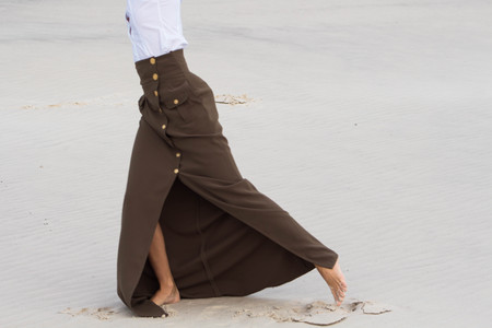 Graceful female legs in a long skirt on white sandの写真素材