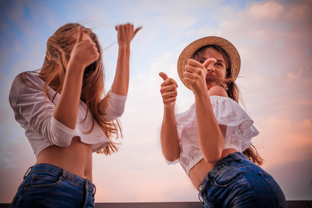 Two happy girls show thumb up coolの写真素材