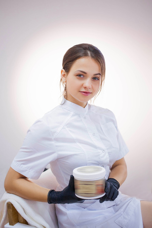 Cosmetologist in white lab coat and black glovesの写真素材