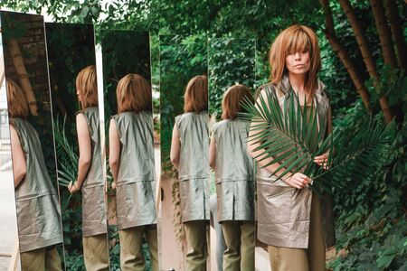 A girl with a lot of mirrors and palm leavesの写真素材